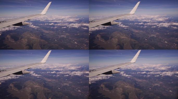 从飞机上可以看到意大利的格兰萨索和蒙蒂德拉拉加国家公园。蓝天上美丽的白堆云的鸟瞰图。舷窗的飞机机翼。