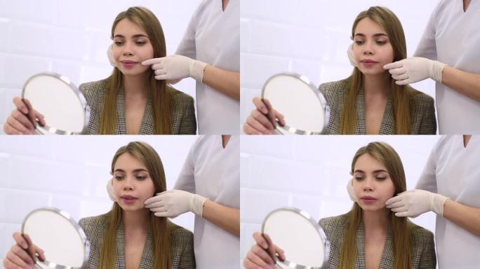 美容诊所的咨询。女美容医生与患者交谈，并用镜子显示年轻女孩的脸部变化。规划美容治疗