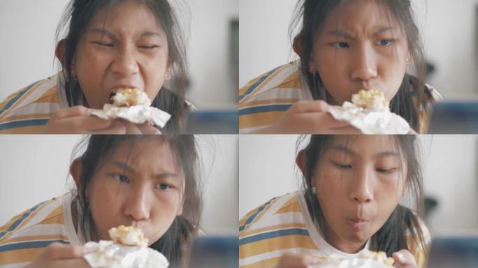 亚洲女孩在家里的窗户附近吃玉米蛋黄包 (玉米面包)，慢动作。