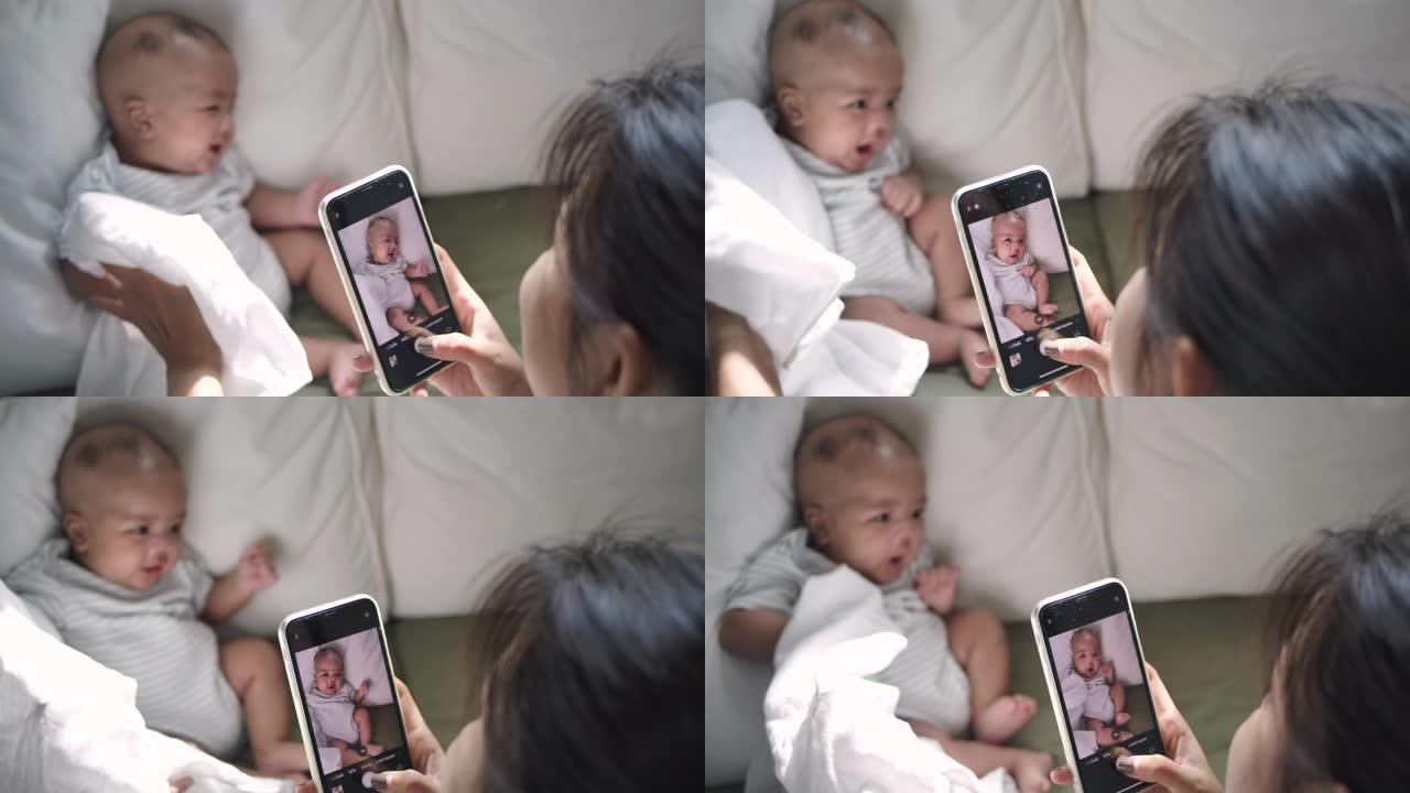 一位母亲正在家里的卧室里用智能手机给孩子拍照