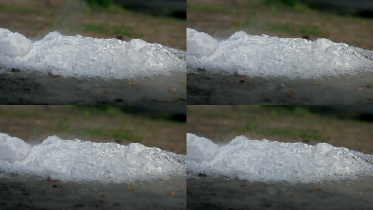 白色的冰块躺在棕色的地面上，并在春季蒸