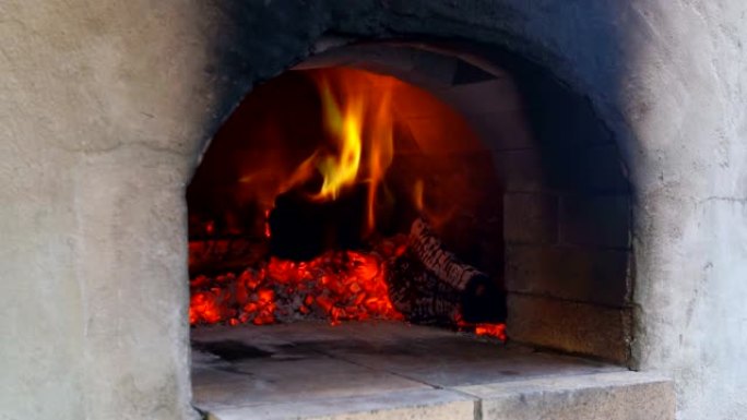 火在披萨烤箱中燃烧，在火烧的热木头在烤箱中烘烤
