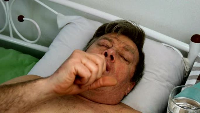 饱受折磨的白人白人男子严重咳嗽，躺在床上。