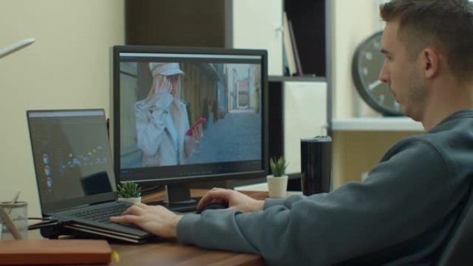 男子摄像师用两台显示器在他的个人电脑上编辑和剪切镜头和声音。