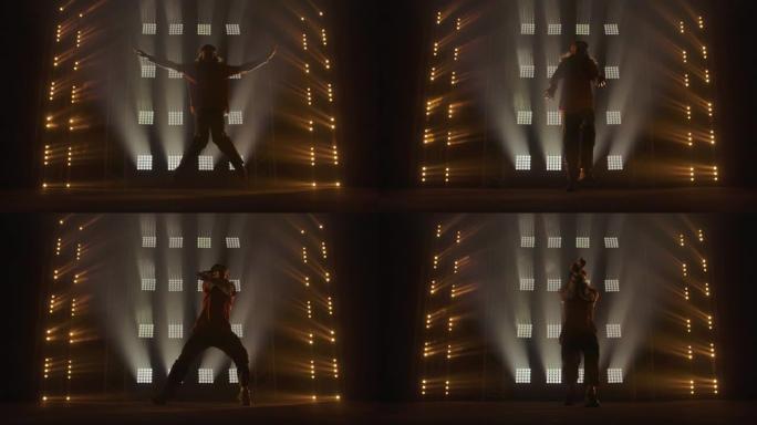 专业的年轻嘻哈舞者，在绿色和黄色的雾中在黑暗的工作室里跳舞。嘻哈文化。彩排。当代