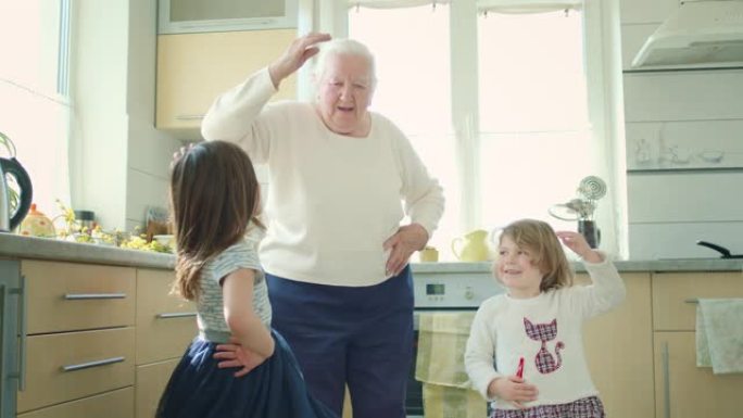 老祖母和两个小曾孙在厨房跳舞。