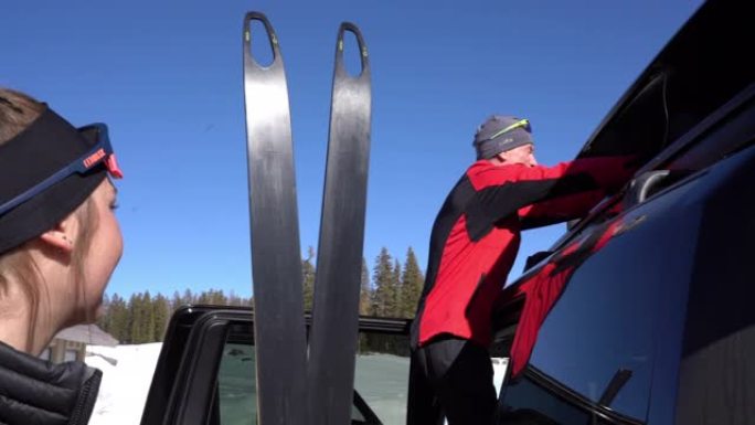 一名男子将滑雪板从车辆后部取出，去越野滑雪。