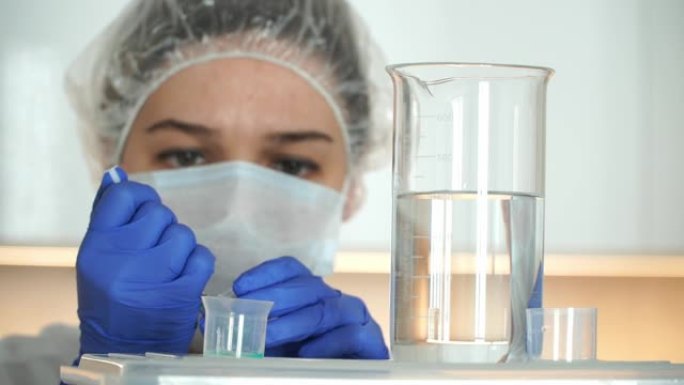 面具和医用手套的科学家女化学家的特写镜头在实验室用烧瓶和药物溶液工作。药物研究的概念。冠状病毒