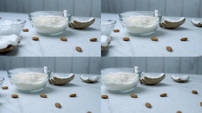玻璃碗中的特写椰子巧克力配料: 椰蓉、枫糖浆、椰子黄油以及装饰性杏仁坚果、椰子片。突出食品成分的概念