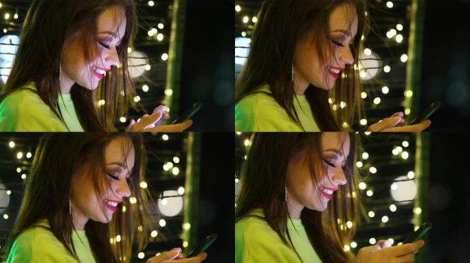 漂亮的女孩看着手机屏幕微笑。真实的微笑年轻20岁女人拿着智能手机