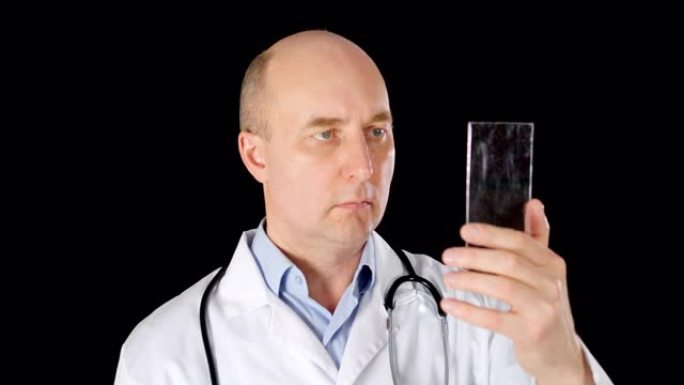 医生在黑色背景上使用透明智能手机上的触摸屏。穿着白大褂的医务工作者触摸未来的手机。现代高科技小玩意概