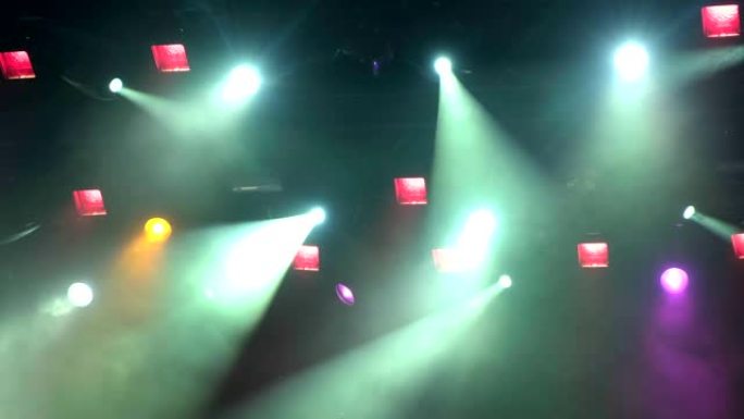 4k uhd手持灯光设备在演出时登上演唱会舞台。聚光灯下的光线穿过烟雾。蓝色和黄色紫色绿色光线