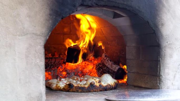 新鲜的原始意大利披萨放在火烧的热木烧披萨中，在烤箱中烘烤