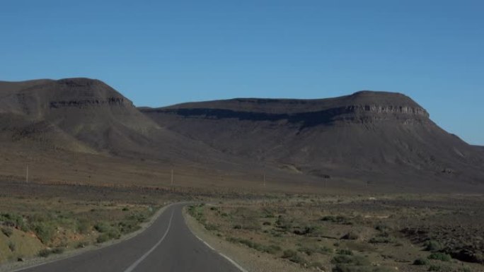 空中低空飞行在摩洛哥大气落基山之间的直沙漠公路上，靠近巨大的落基山和美丽的天空。