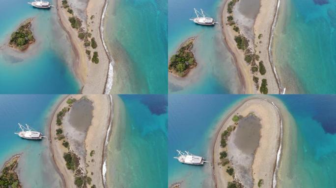土耳其水蓝色水中的船的天线，天堂般的感觉海滩上清澈的海水，海滩蓝白色的沙子向下拍摄