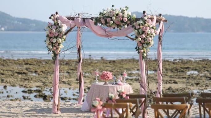 海滩上户外用布和鲜花装饰的婚礼拱门。