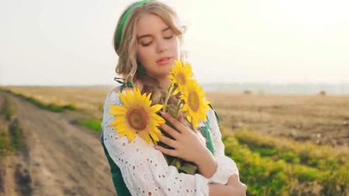 肖像年轻美丽的女人。花束黄色向日葵。巴伐利亚美女享受夏日大自然蓝天。模糊的背景农村道路麦田花。自然化