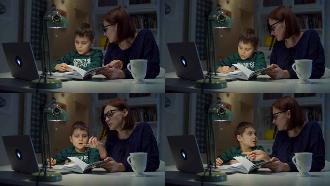 30多岁的年轻母亲在家和小学生儿子一起做在线作业。戴眼镜的女人和男孩用笔记本电脑，笔记本电脑和教科书