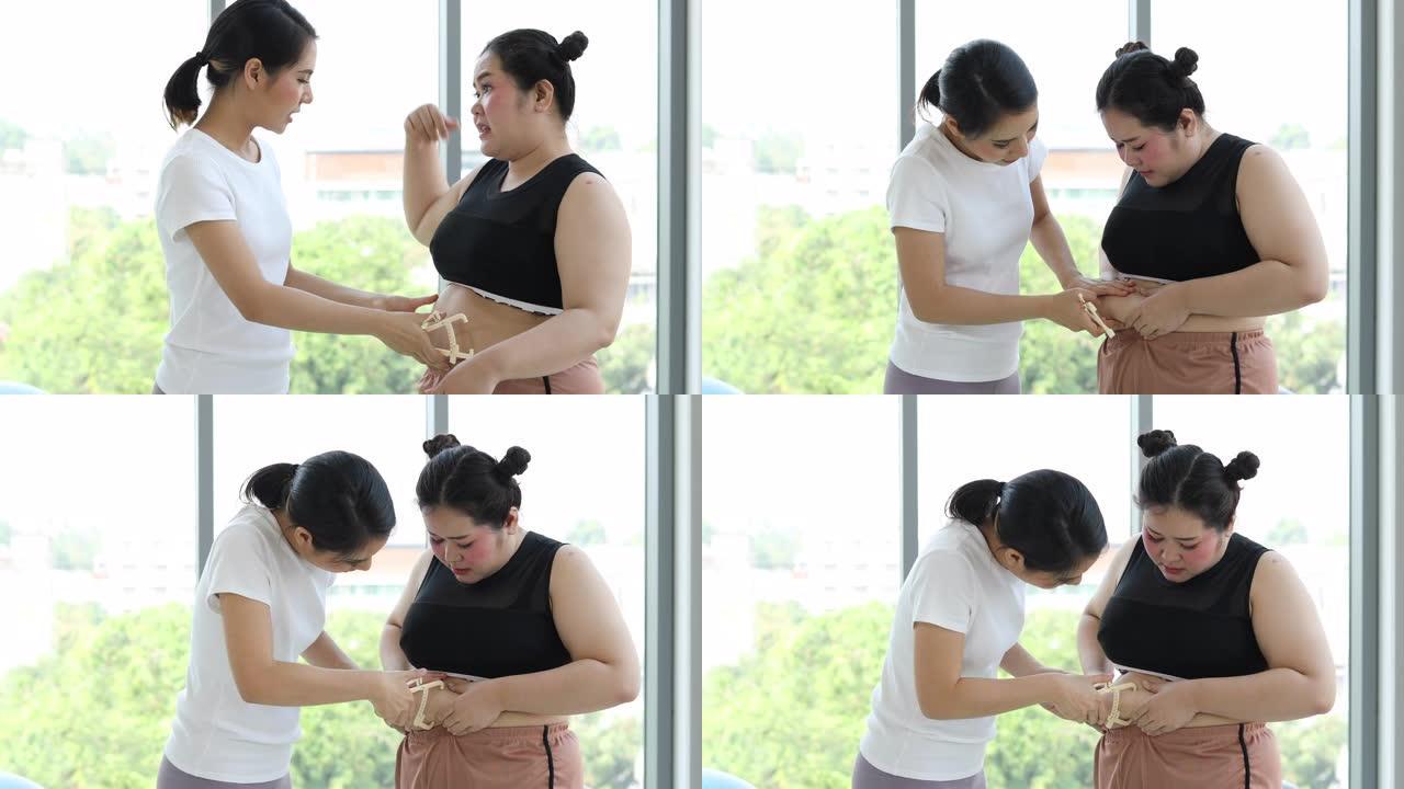 年轻的女教练在健身时用卡尺测量超重妇女的脂肪层