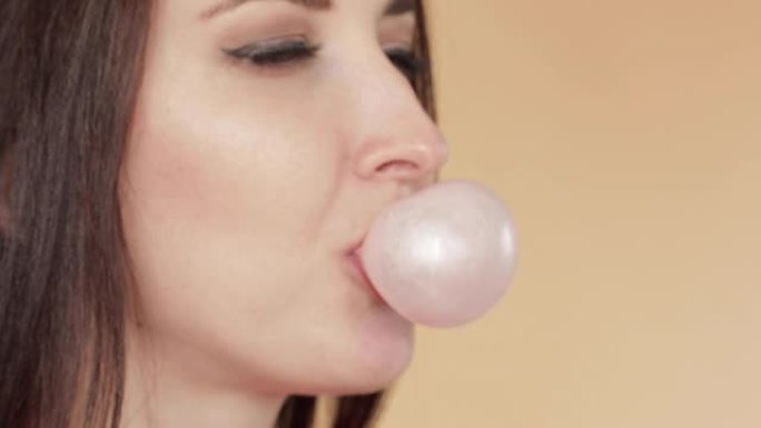 年轻女子吹粉红色泡泡糖的侧视图