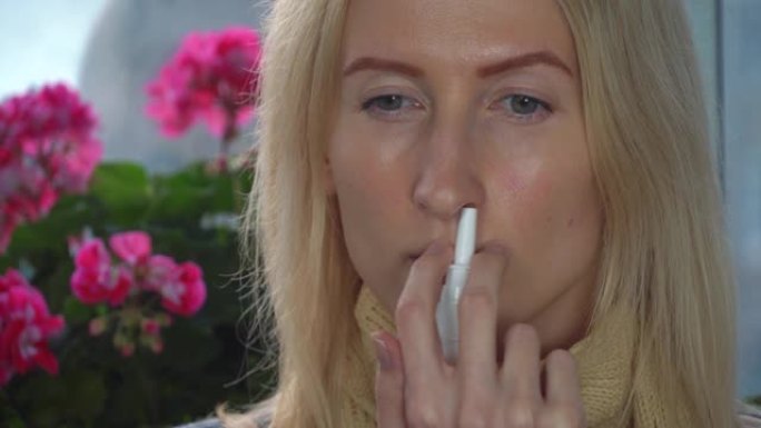 一名妇女在家中使用鼻腔喷雾剂治疗对花卉和植物的花粉过敏。