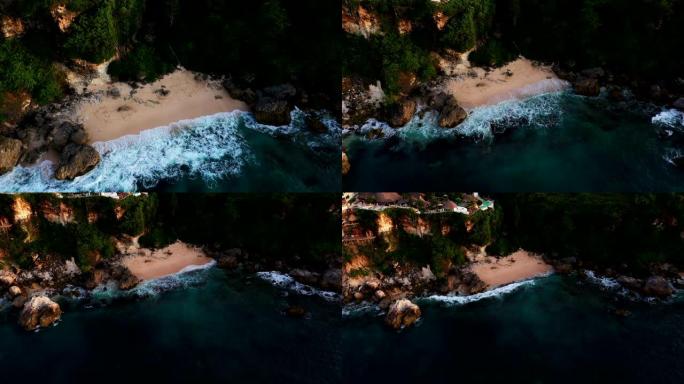 无人机空中俯视图移动远离海洋蓝色海浪碰撞海岸线悬崖金色沙滩清洁海滩。水大理石水晶清澈的盐水。日落时，