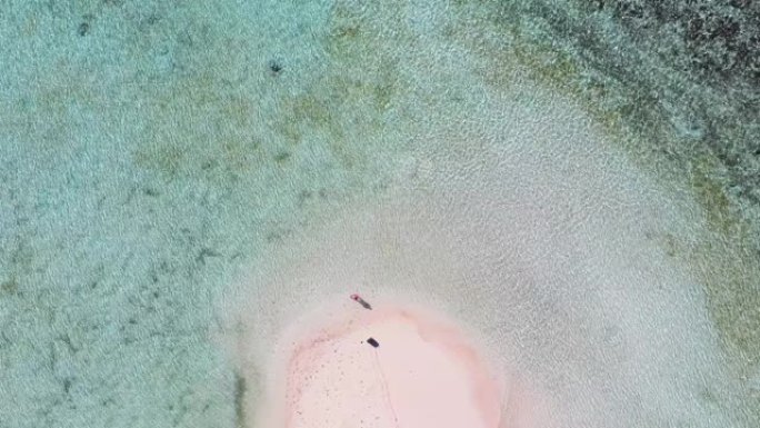 空中宽镜头女子独自站在粉红沙滩岛上