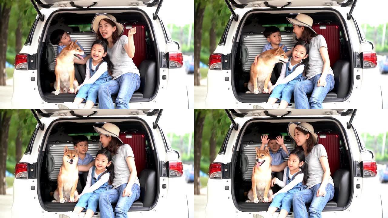 快乐的亚洲儿童和母亲与shiba inu坐在车里唱歌。