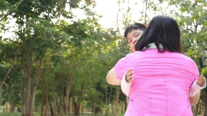 慢动作亚洲小男孩带着温暖的微笑用爱拥抱母亲。关于家庭价值观的概念，在公园户外的感觉和情感