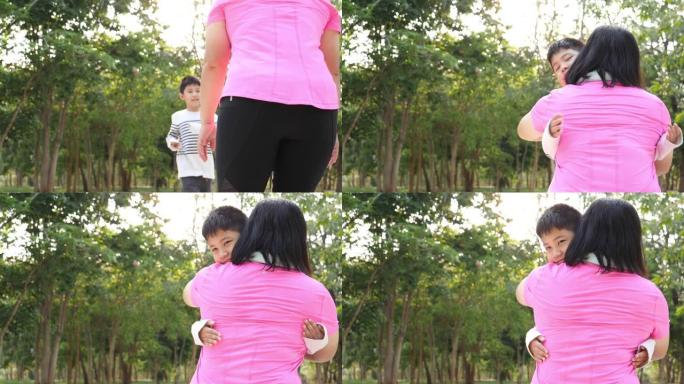 慢动作亚洲小男孩带着温暖的微笑用爱拥抱母亲。关于家庭价值观的概念，在公园户外的感觉和情感