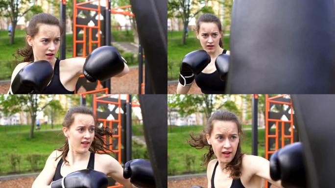 在街头城市训练场用出气筒训练严肃的女拳击手。稳定的镜头，慢动作。自卫队