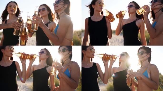穿着比基尼的漂亮女人在日落时在沙滩上享受着烤饮料和放松的乐趣。穿着泳衣的女孩，戴着啤酒瓶挂在海边的太