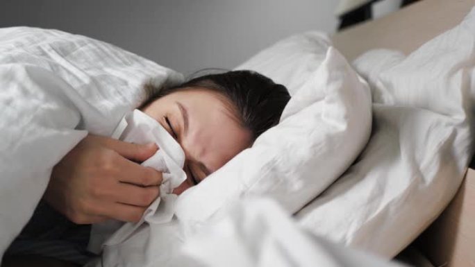 流鼻涕的女人躺在床上，她从纸盒餐巾里出来，在里面吹鼻子。感冒，流感，过敏，灰尘，猫毛，鼻炎，体温过低