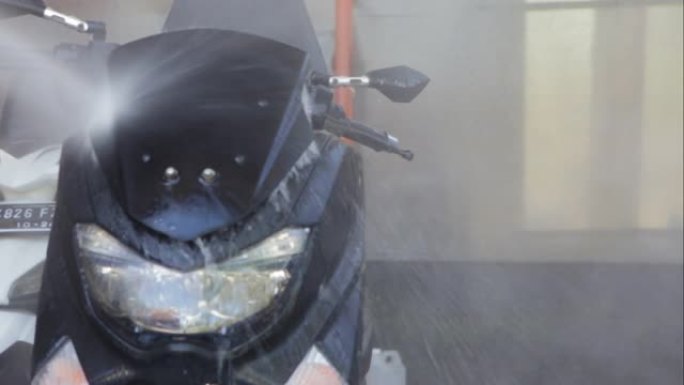 在家或洗车站用喷水清洗摩托车。摩托车或踏板车清洁