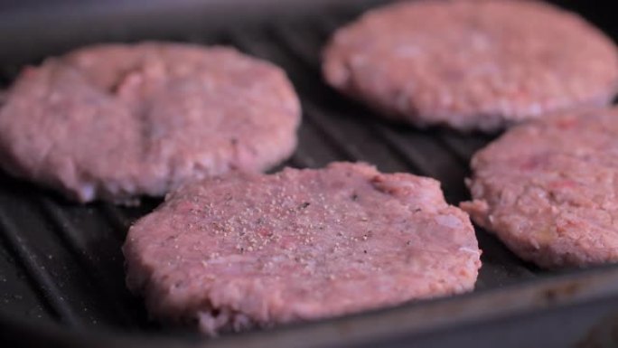 将胡椒粉撒在肉上，用于黑锅上的汉堡。
