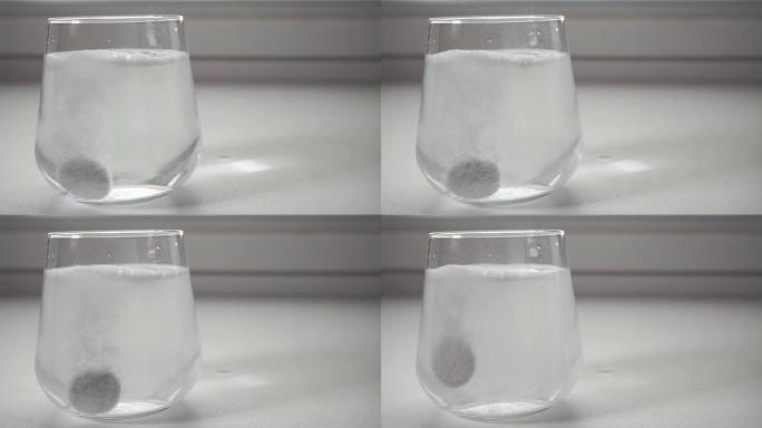 可溶性片剂掉在白色背景上的一杯水中