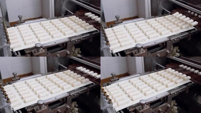 糖果厂的生产线上的糖果与巧克力一起倒入。甜食生产线。干酪棒的制造工艺。食品工厂