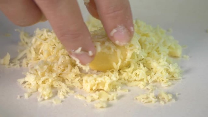 女人的手在磨碎的奶酪上滚动一个coockie面团球，关闭makro射击厨师手指