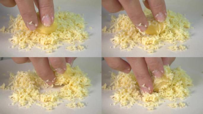 女人的手在磨碎的奶酪上滚动一个coockie面团球，关闭makro射击厨师手指