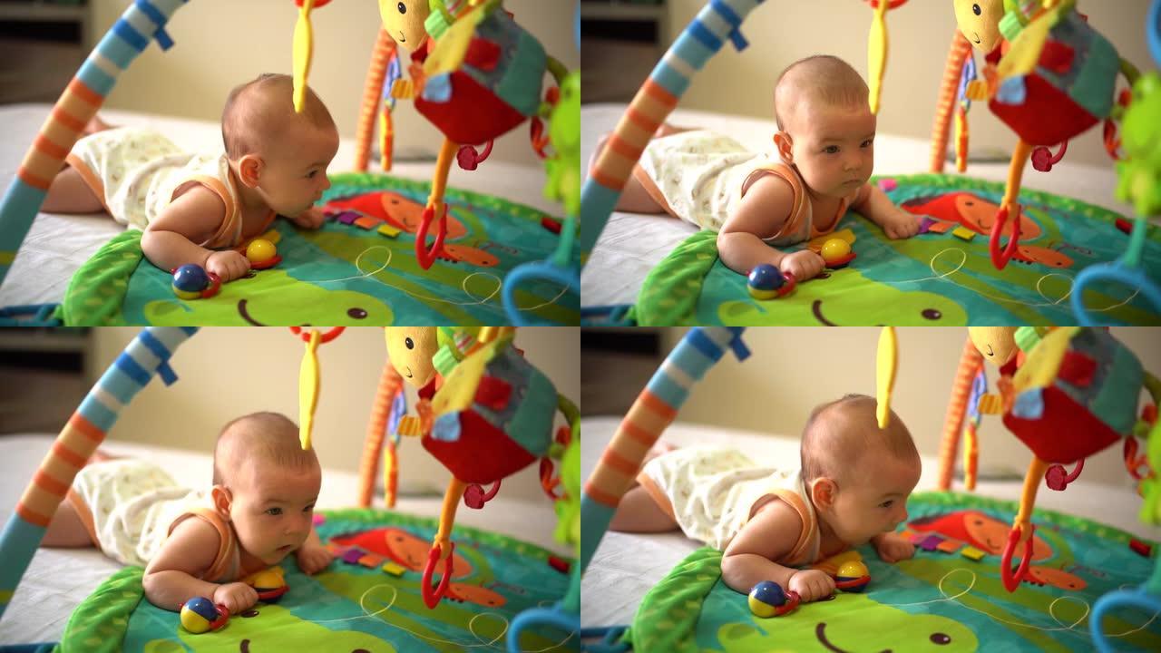 手里拿着拨浪鼓的婴儿，试图在游戏开发垫上爬行