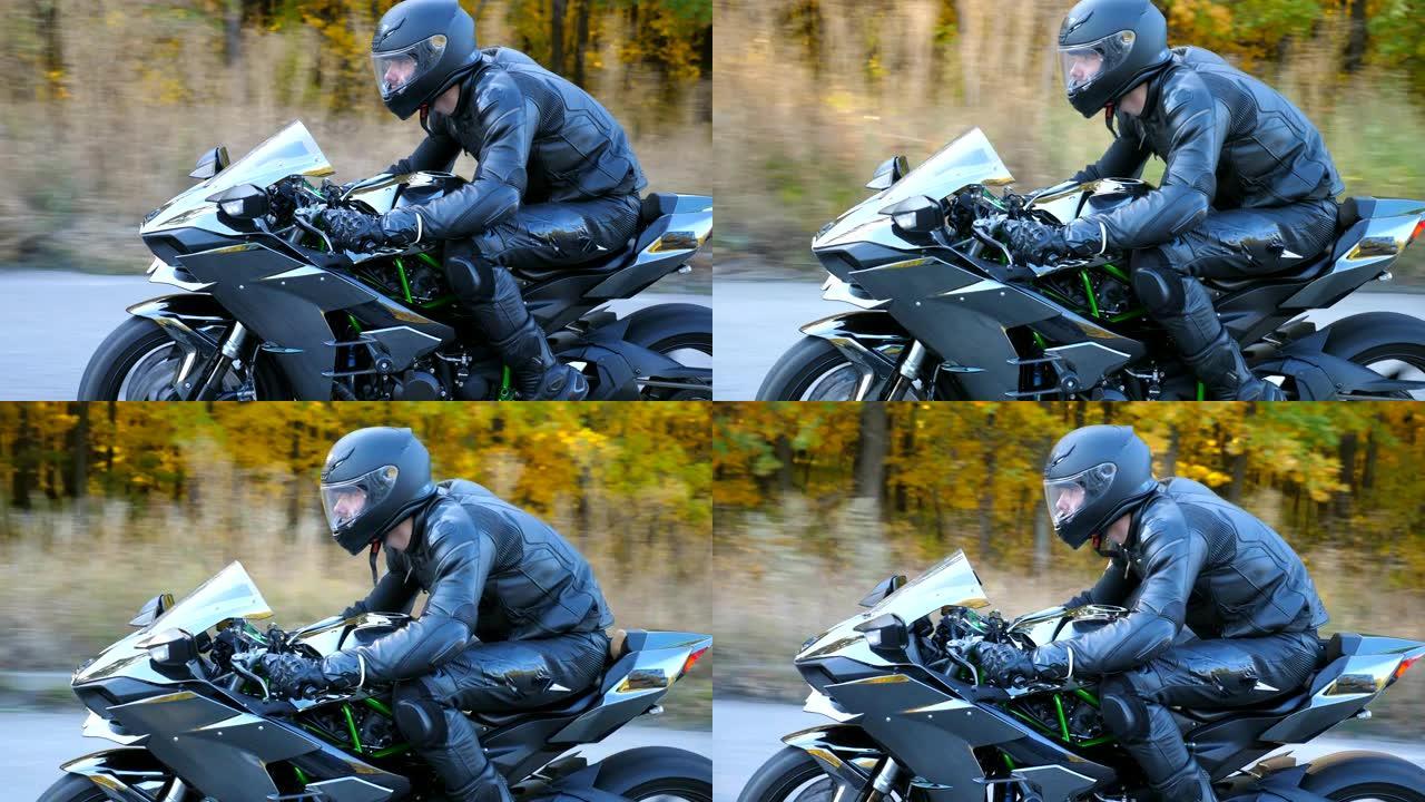 摩托车手在乡间小路上骑摩托车。旅途中开车的人。戴着头盔的年轻人在高速公路上快速骑现代运动摩托车。侧视