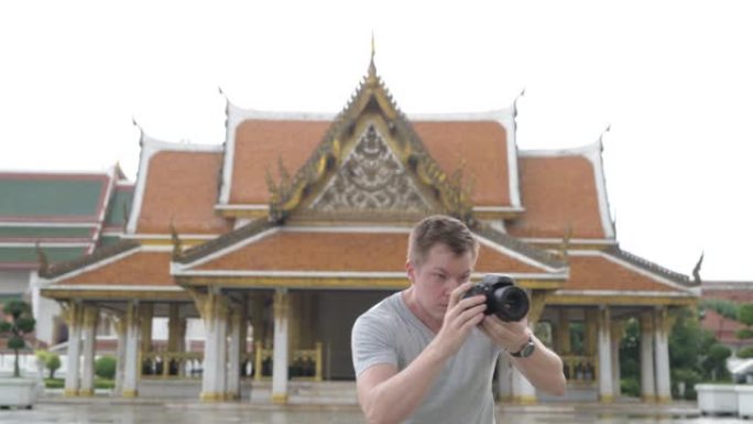 年轻快乐的旅游男子在曼谷佛教寺庙周围拍照