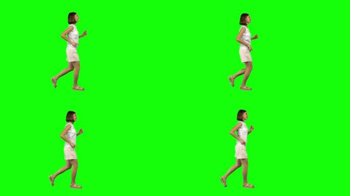 棕色头发和光滑发型的年轻女子在绿色屏幕上微笑着奔跑。色度键，4k镜头。纵断面视图