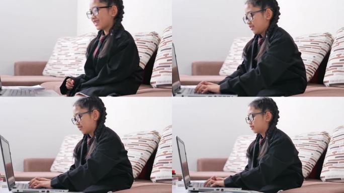 一个戴着眼镜，穿着黑色西装的亚洲小女孩，一个坐在棕色沙发上的女商人正在幸福地在笔记本电脑上打字。
