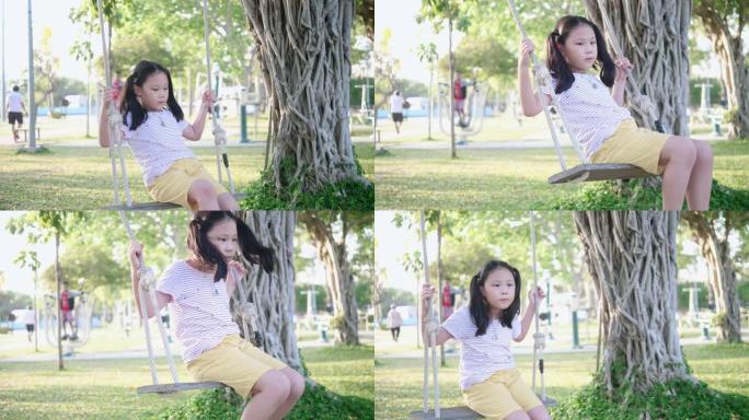 快乐的亚洲女孩在公园户外玩秋千，慢动作。