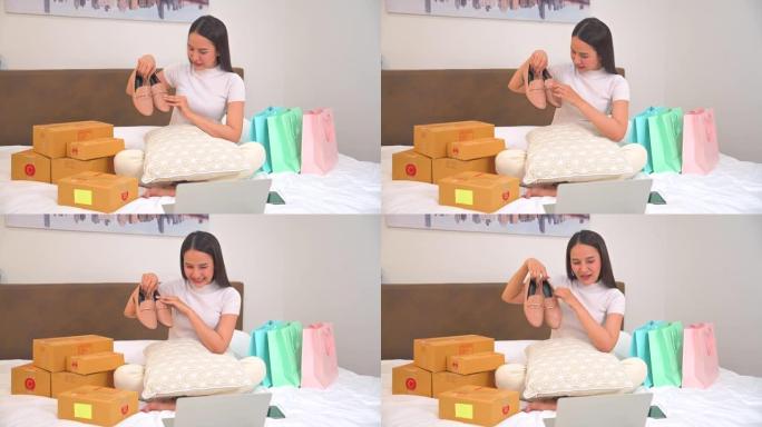 亚洲年轻女子与顾客交谈，在家里的床上在线展示和销售产品，同时坐在前置摄像头中录制视频并通过互联网向社