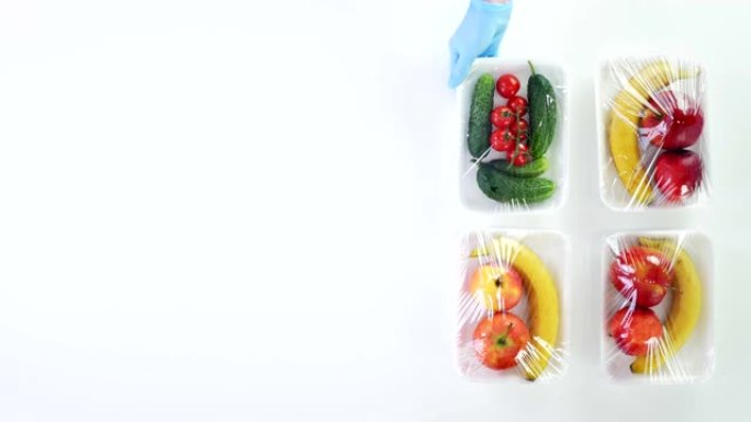 俯视图，双手戴上防护手套，将蔬菜，水果包装放在纸板箱旁边，以包装杂货店，以进行送货。网上购物。送餐。