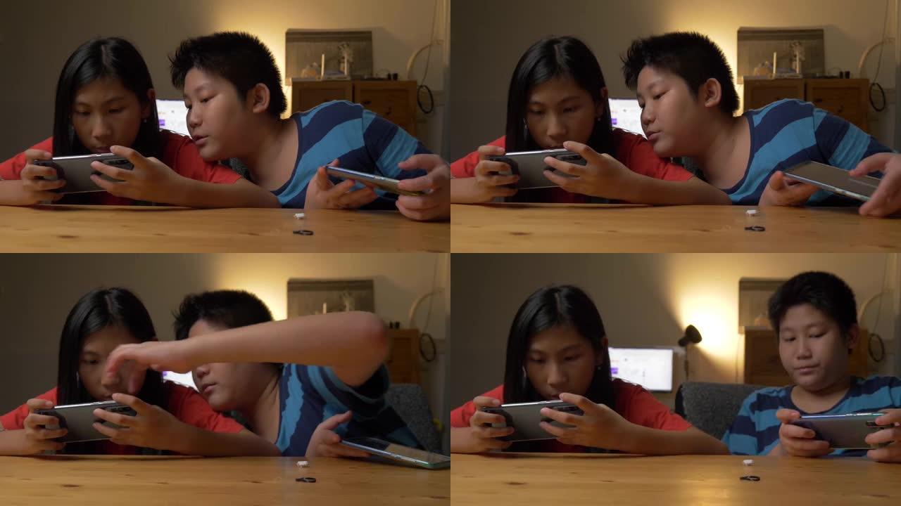 快乐的亚洲兄妹在家里一起玩网络游戏。