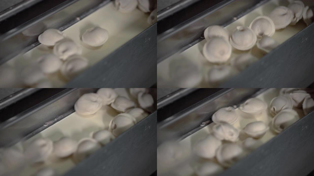 饺子厂的自动机器生产过程。新鲜的生水球落在传送带上。在食品工厂运行的工业机械。