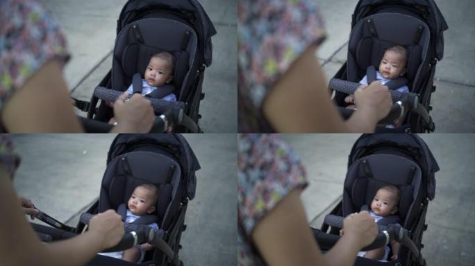 母亲带着婴儿车的男婴穿过公园
